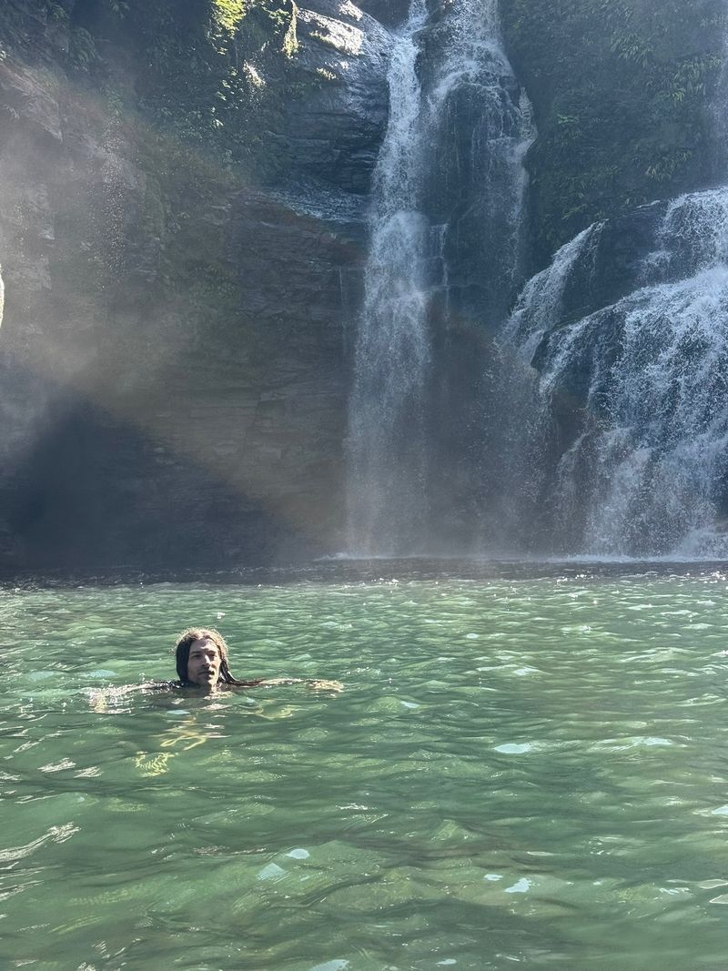Joshua swimming in the pool at the bottom of a waterfall